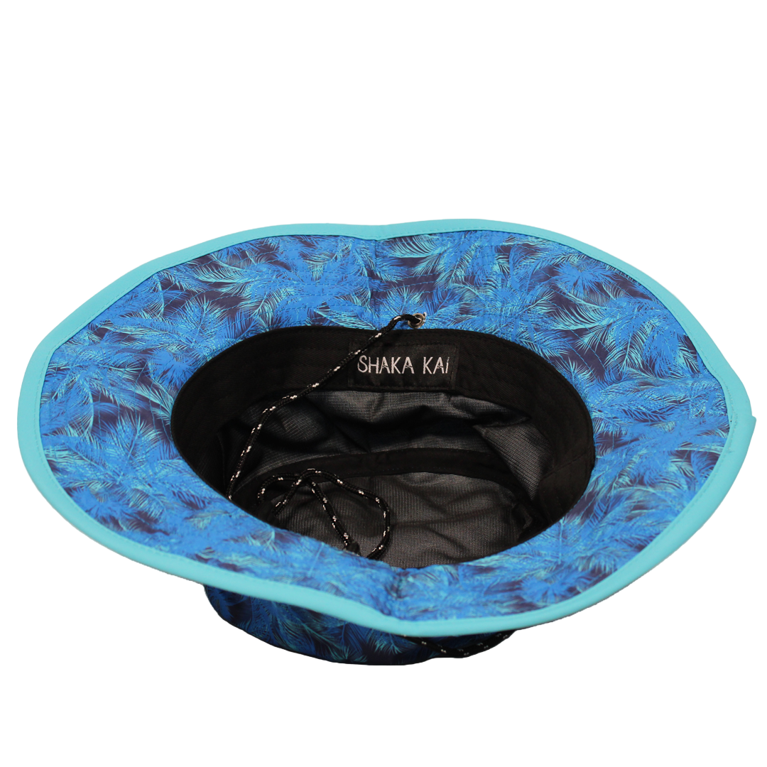 Blue floral-patterned bucket hat with sun protection and a black interior and 'Shaka Kai' branding on a white background