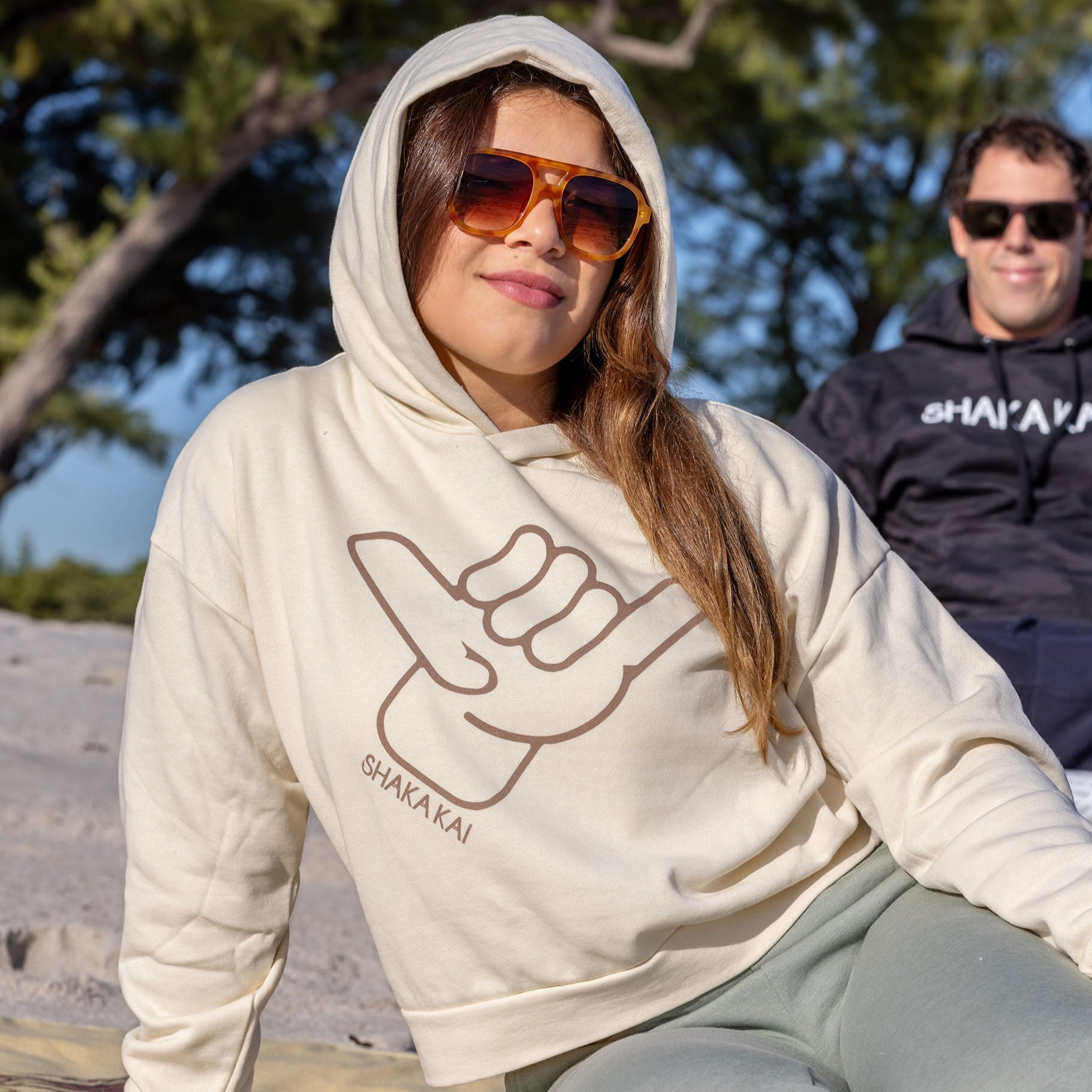Woman wearing an Icon Womens Hoodie with a shaka sign, showcasing everyday comfort and island style.
