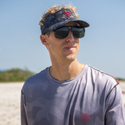 Camo Visor worn by a man on the beach, showcasing style and functionality with sunglasses.